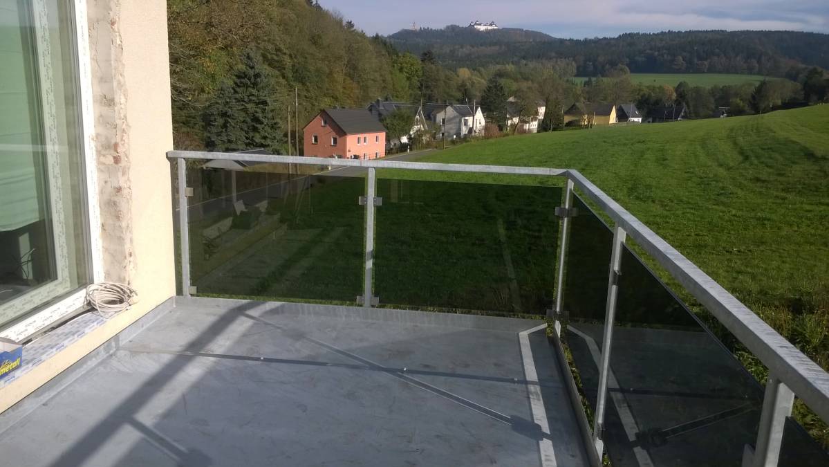 Balkon an Eigenheim für bauseitigen Belag vorbereitet, Geländer mit Glasfüllung.