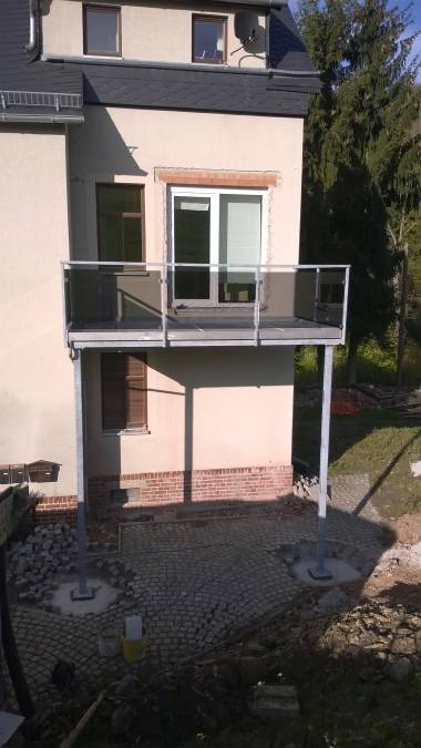 Balkon an Eigenheim für bauseitigen Belag vorbereitet, Geländer mit Glasfüllung.