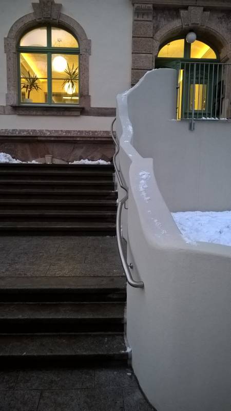 Edelstahlhandlauf parallel zur geschwungenen Betonwand am Eingang der Ludwig Richter Grundschule