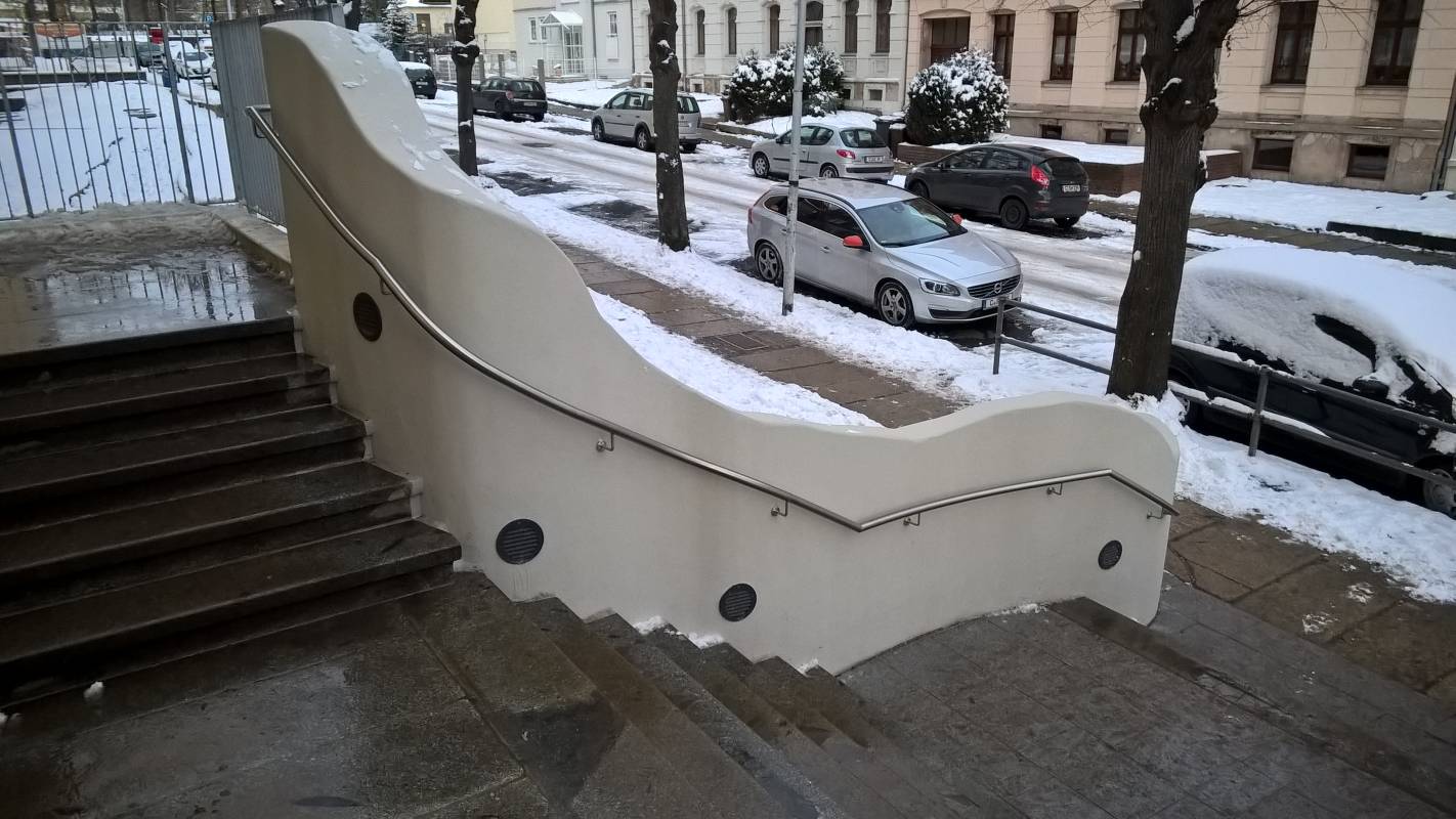 Edelstahlhandlauf parallel zur geschwungenen Betonwand am Eingang der Ludwig Richter Grundschule