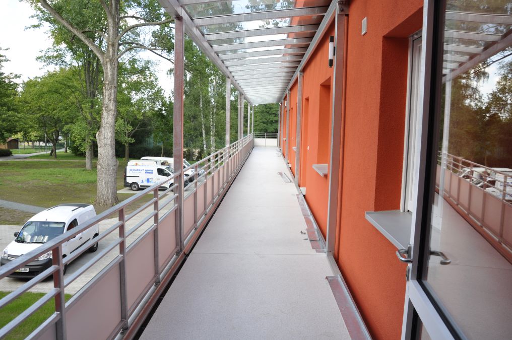 Laubengänge mit Glasüberdachung und Balkone an einem Wohnhaus